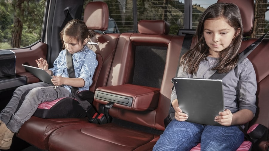 Two children using mobile devices with the available in-vehicle Wi-Fi hotspot