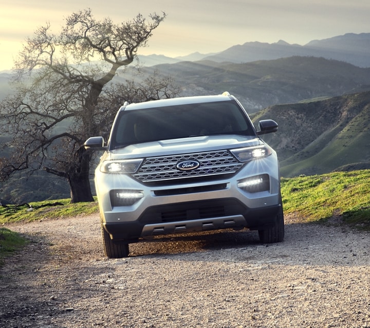 A 2022 Ford Explorer Platinum edition being driven up a mountain road with scenic mountain range in the background