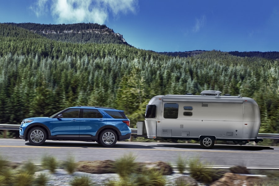 2022 Ford Explorer Hybrid in Atlas Blue pulls a camper on the highway
