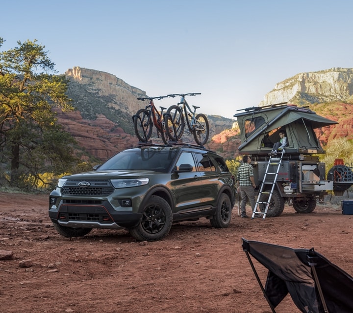 2022 Ford Explorer Timberline parked in a mountainous desert with a pop-up trailer and two women walking