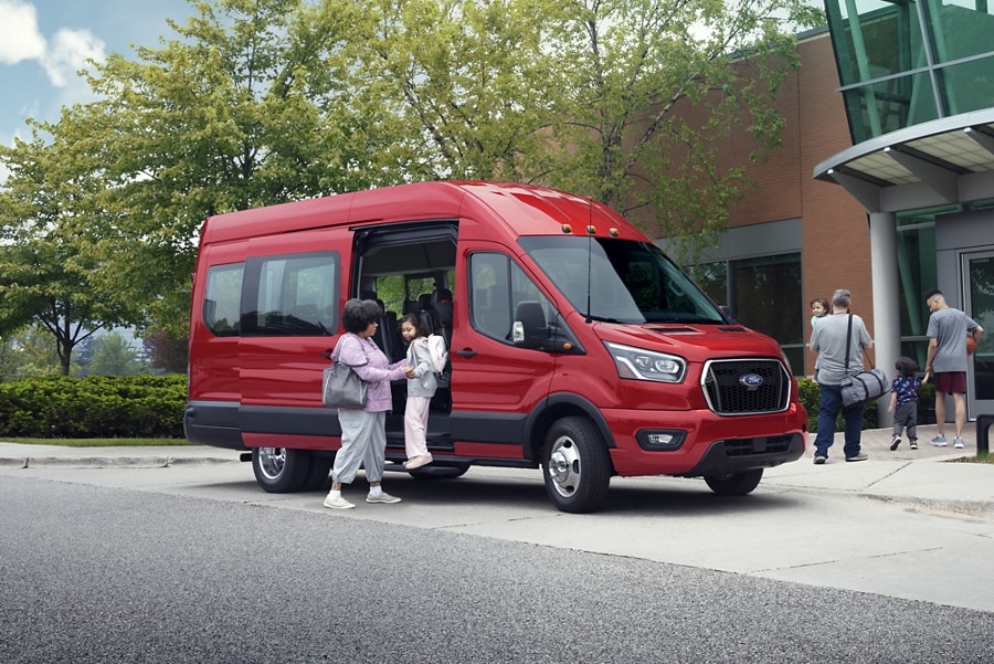 A woman helping a young girl out of a 2023 Ford Transit® van