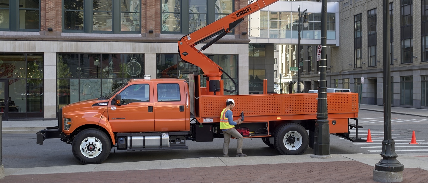 Workers changing city streetlights using 2024 Ford F-750 Crew Cab with aerial lift upfit in Tangier Orange