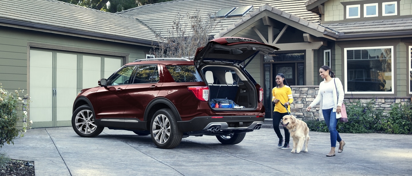 2022 Ford Explorer with a mom and daughter walking their dog toward the open liftgate