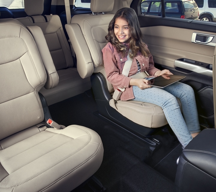 2022 Ford Explorer with tan interior and a young girl sitting in second-row seat holding a tablet computer