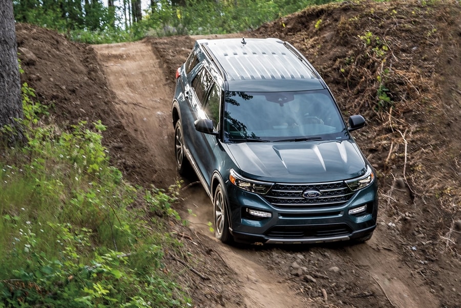 2022 Ford Explorer Limited in Atlas Blue being driven down a steep dirt hill in a woodsy environment