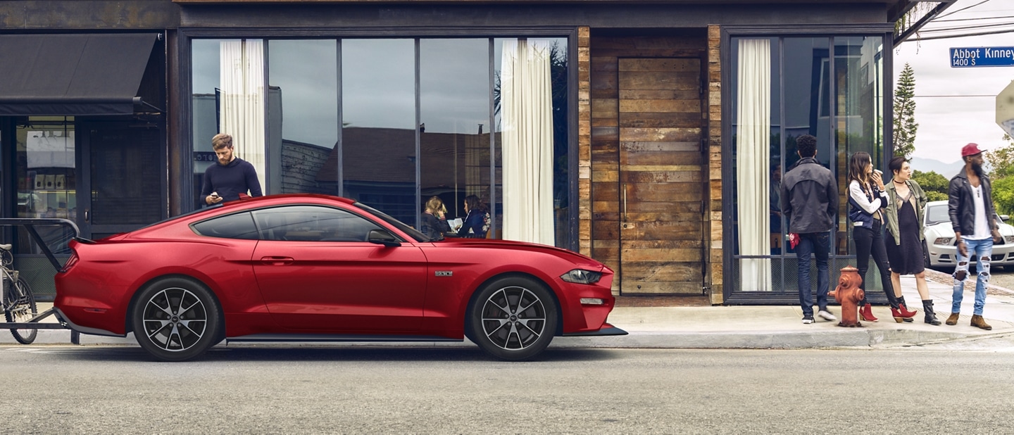 A 2023 Ford Mustang® coupe parked near a storefront with a person in the foreground