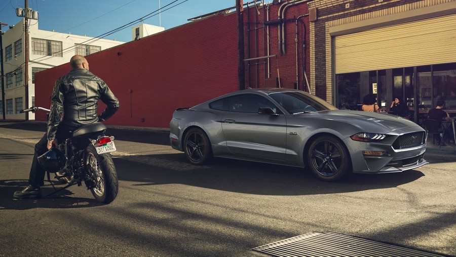 Person on a motorcycle admiring a parked 2023 Ford Mustang® coupe