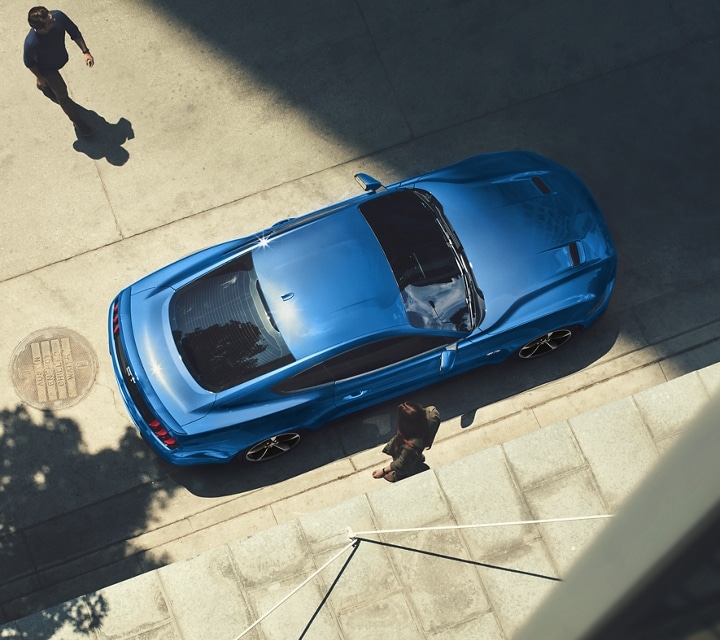 Overhead view of a 2023 Ford Mustang® coupe parked on a street with a person approaching