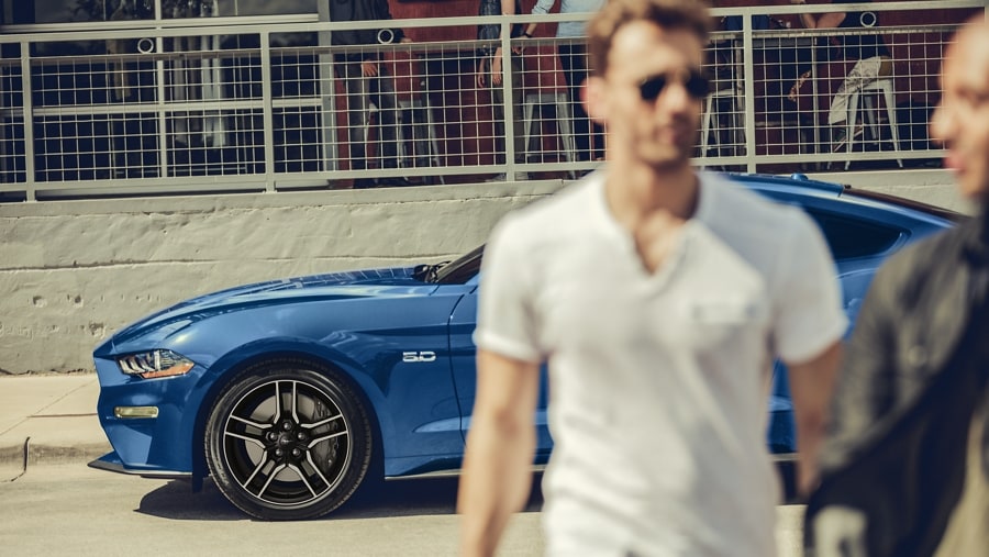 Two people walking away from a Mustang® coupe with 18-inch x 8-inch wheels