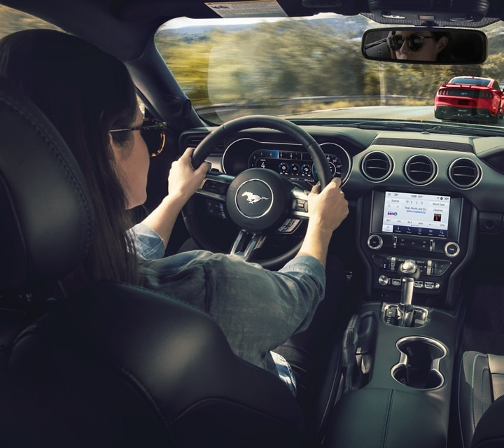 Person behind the wheel of a 2023 Ford Mustang® coupe driving on a mountainous road