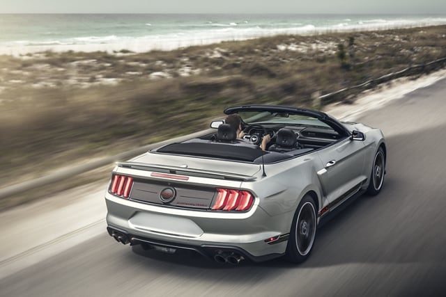 Rear view of a 2023 Ford Mustang® convertible being driven down an oceanside highway