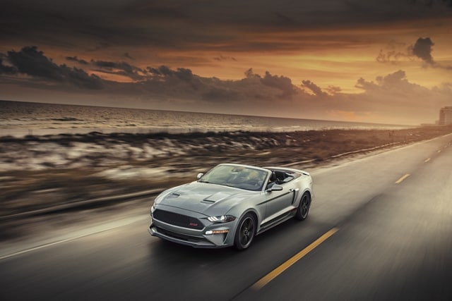 2023 Ford Mustang® convertible with California Special Package with the top down, being driven on an oceanside highway
