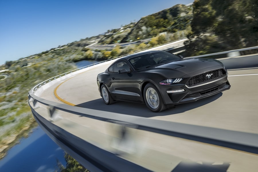 A 2023 Ford Mustang® coupe in Shadow Black being driven around a curve on a mountain road