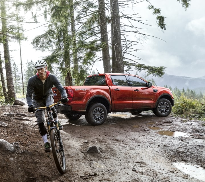 2023 Ford Ranger® in Hot Hepper Metallic parked in woods with cyclist pedaling away