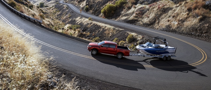 2023 Ford Ranger® XLT in race red towing a boat up a road