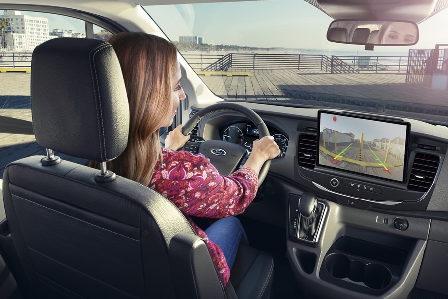 A woman driving a 2023 Ford Transit® van looking at the touchscreen