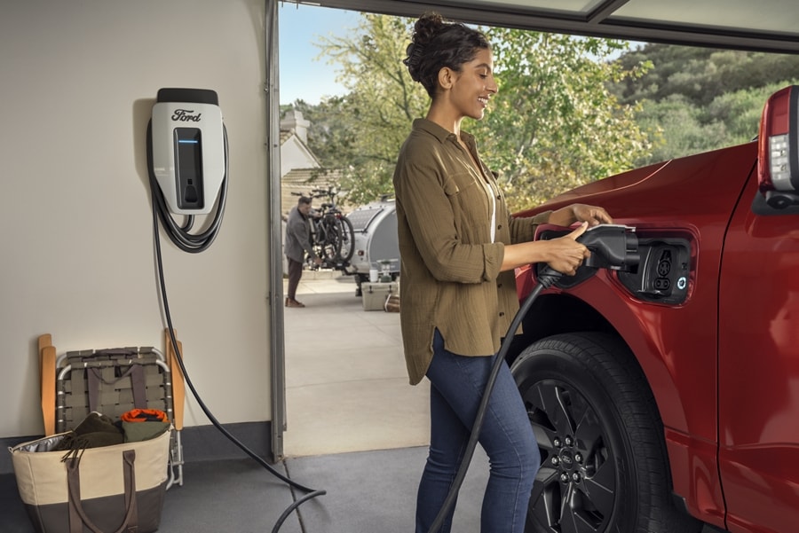 A woman begins to charge a 2023 Ford F-150® Lightning® in her garage