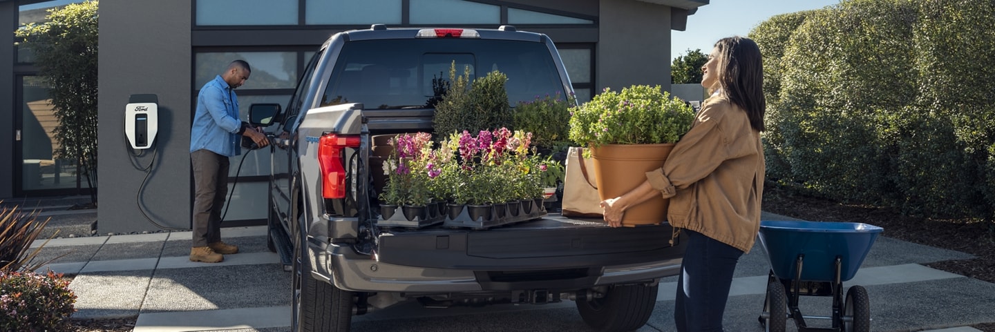 A woman unloading flowers from the bed of a 2023 Ford F-150 Lightning®