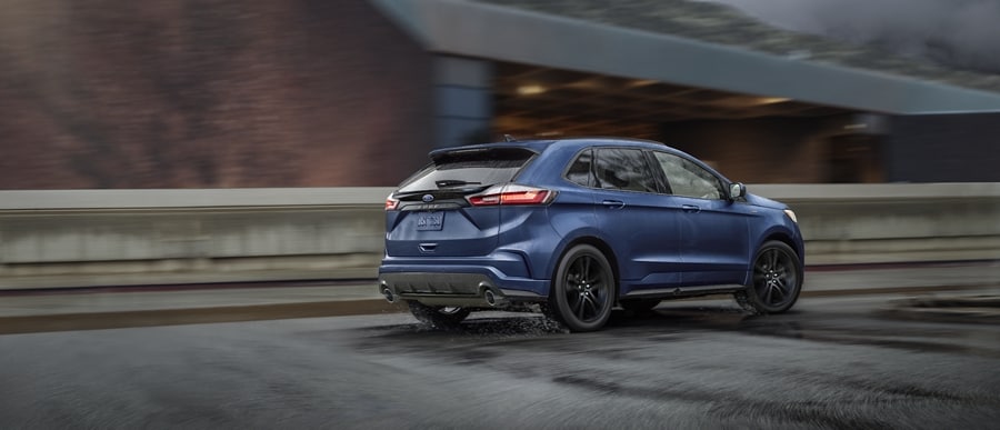 2023 Ford Edge® ST-Line in Stone Blue being driven on a road with overpass in background