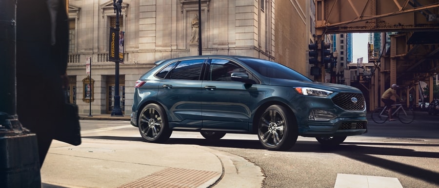 2023 Ford Edge® ST model in Sone Blue driving around a curve in a city