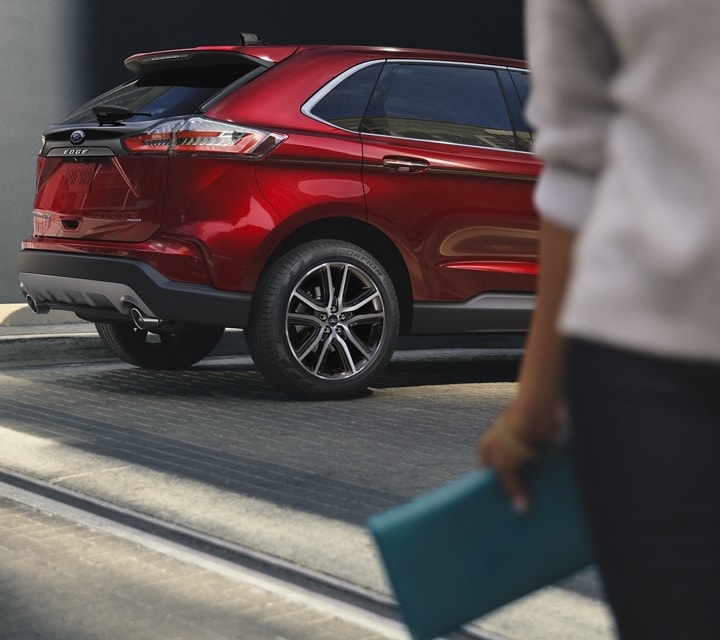 Woman walking away from a parked 2023 Ford Edge® SUV in Rapid Red