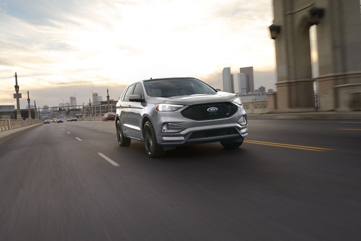 2023 Ford Edge® SUV being driven down a road with a city in the background