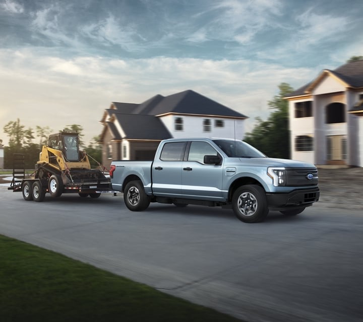 A silver 2023 Ford F-150® Lightning® parked in front of a home construction site
