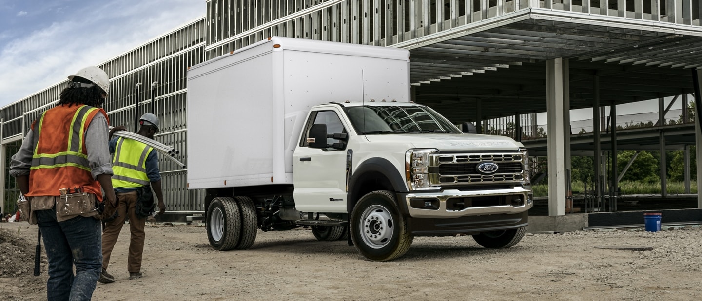 Workers approaching a 2023 Ford Super Duty® F-600® in Oxford White with box truck upfit
