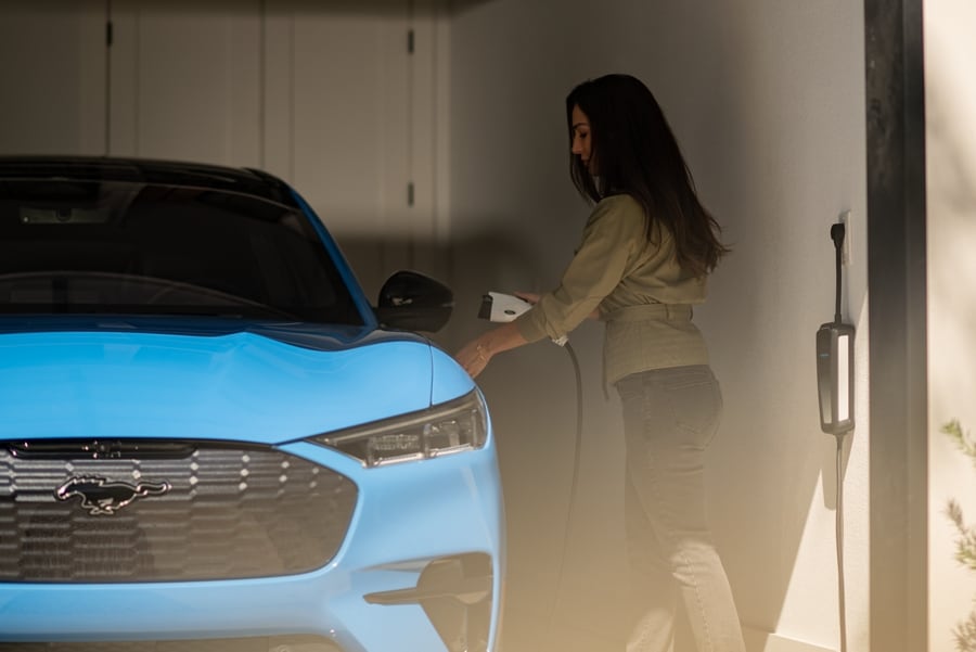 A woman begins to charge a 2023 Ford Mustang Mach-E® in her garage