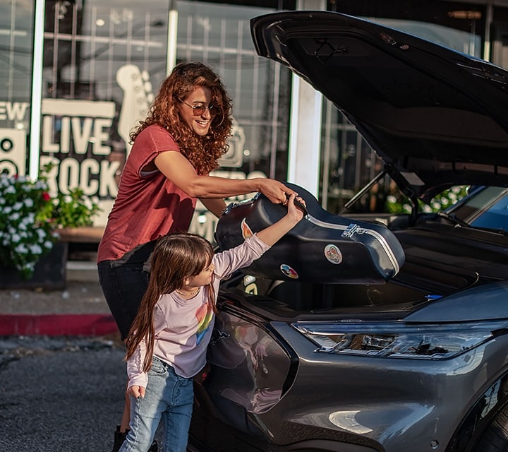 Woman helps child put a musical instrument into the frunk of a 2023 Ford Mustang Mach-E® SUV