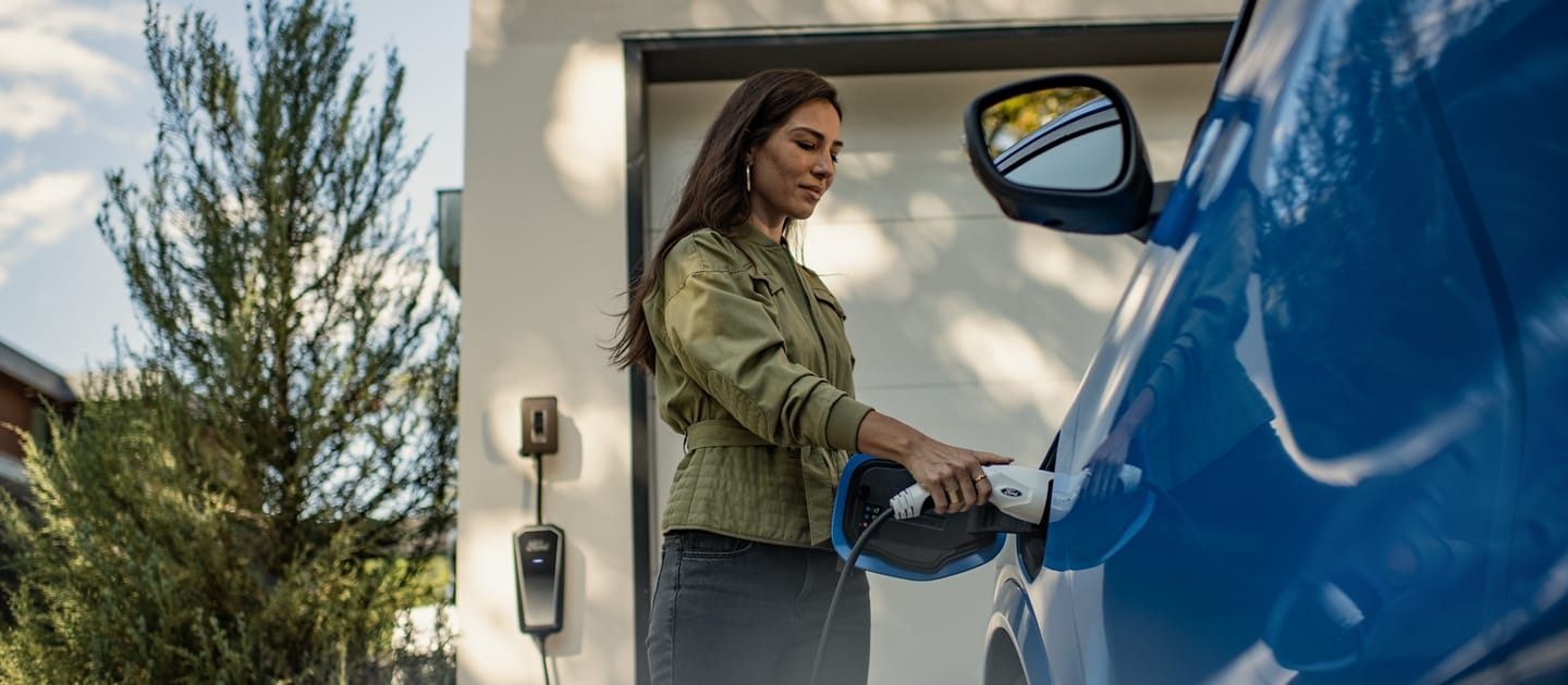 A woman begins to charge a 2023 Ford Mustang® Mach-E® at her home