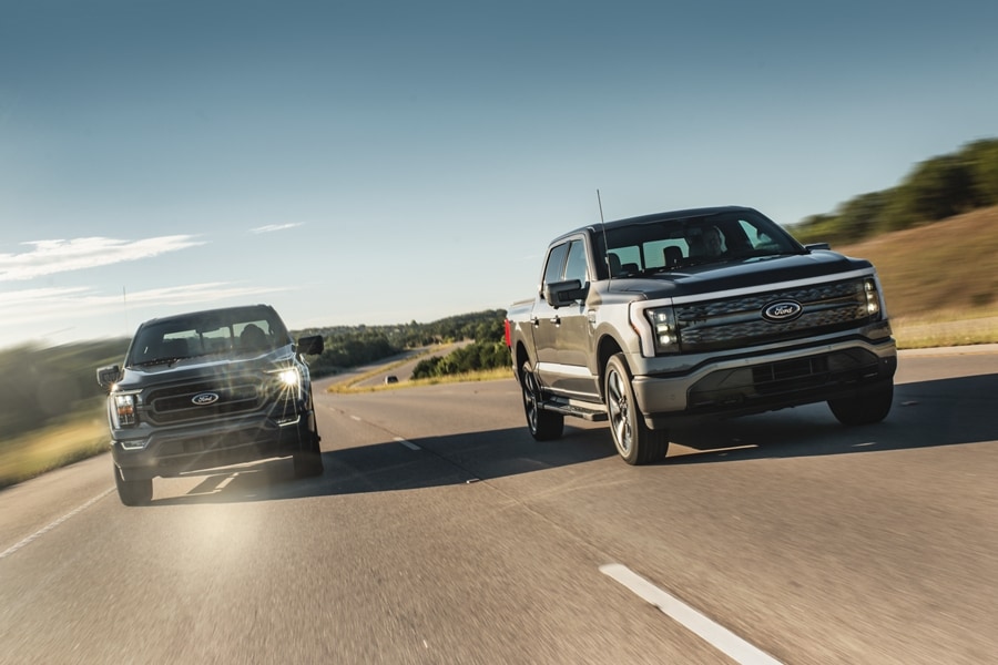 A Ford F-150 Lightning truck passes a Ford F-150 truck on an open highway.