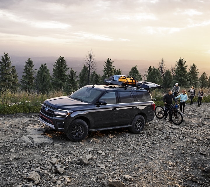 A 2024 Ford Expedition SUV parked on a rocky road with family getting ready to ride bicycles