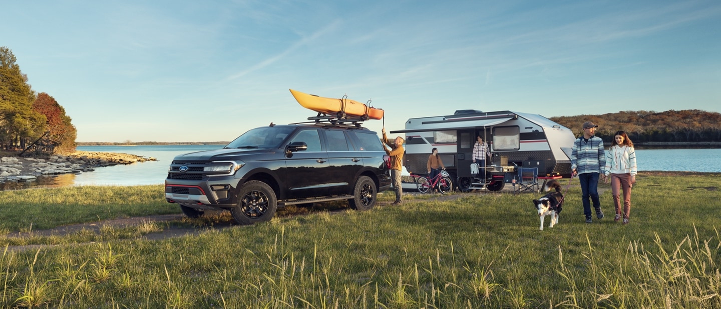 A 2024 Expedition Timberline parked by a lake with a camper and family