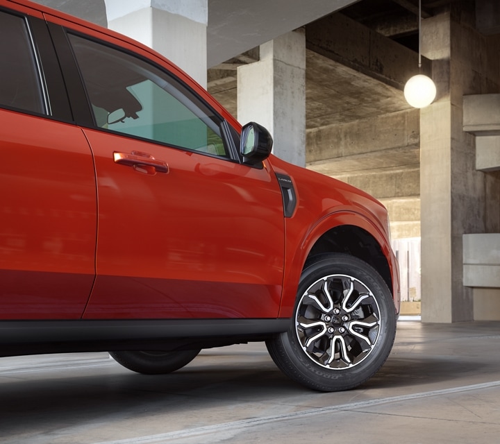 A 2024 Ford Maverick® in Hot Pepper Red is parked in a garage with a view of the wheel