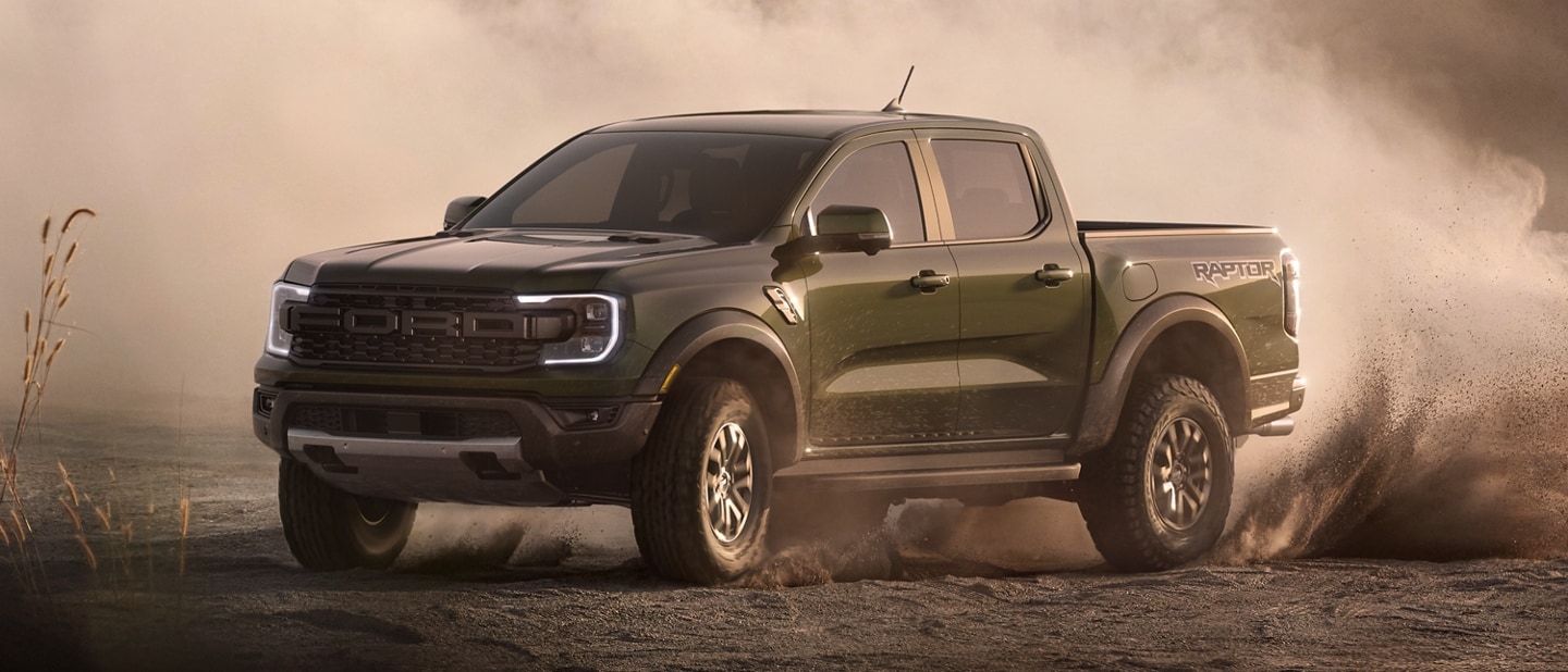 A 2024 Ford Ranger® Raptor® in Hot Pepper Red with an extra cost option is being driven in a desert location