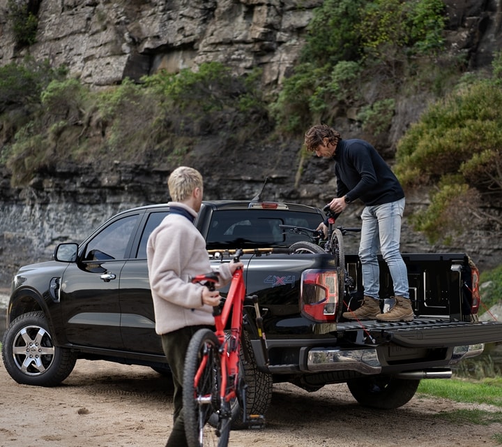 Two people are loading gear into the bed of a 2024 Ford Ranger® in Agate Black