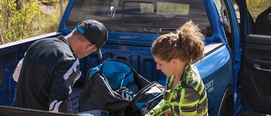 Close-up of two people loading gear near the back of their 2024 Ford Ranger® in Velocity Blue