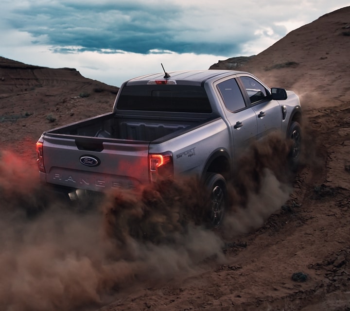 A 2024 Ford Ranger® in Velocity Blue is being driven up a sandy dune