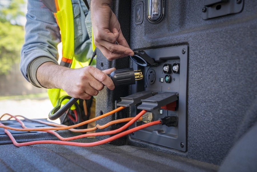 Close-up of a person plugging a cord into the Pro Power Onboard outlet in the bed of a 2022 Ford F-150®