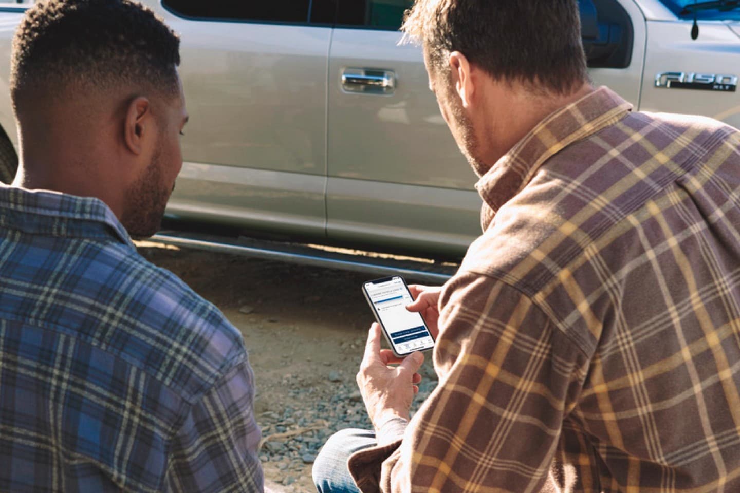 Two men looking at the Ford Pro™ Telematics Drive app on a smartphone
