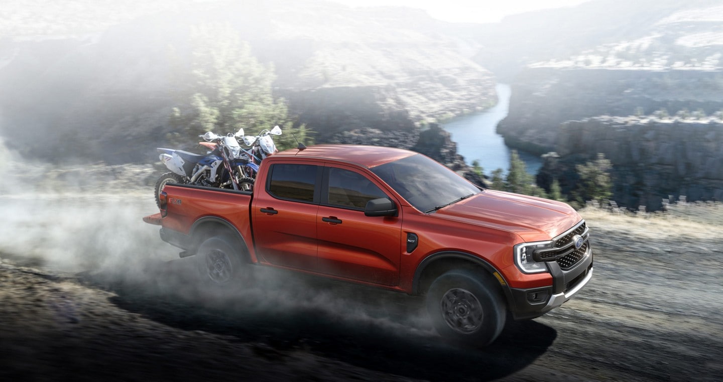 A 2024 Ford Ranger® in Hot Pepper Red with an extra cost option with dirt bikes being hauled and driven off-road