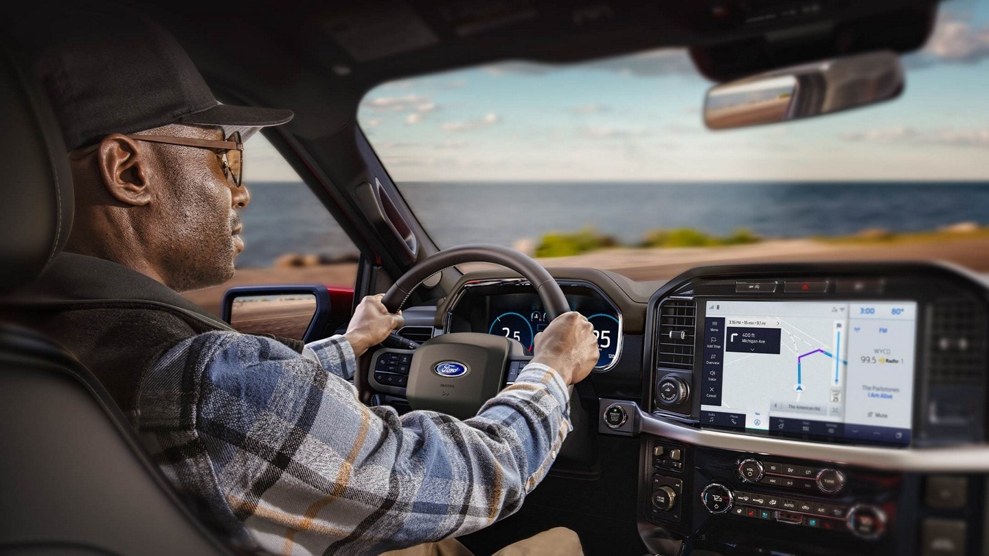 Person driving with view of touchscreen showing SYNC® 4 available cloud-connected navigation