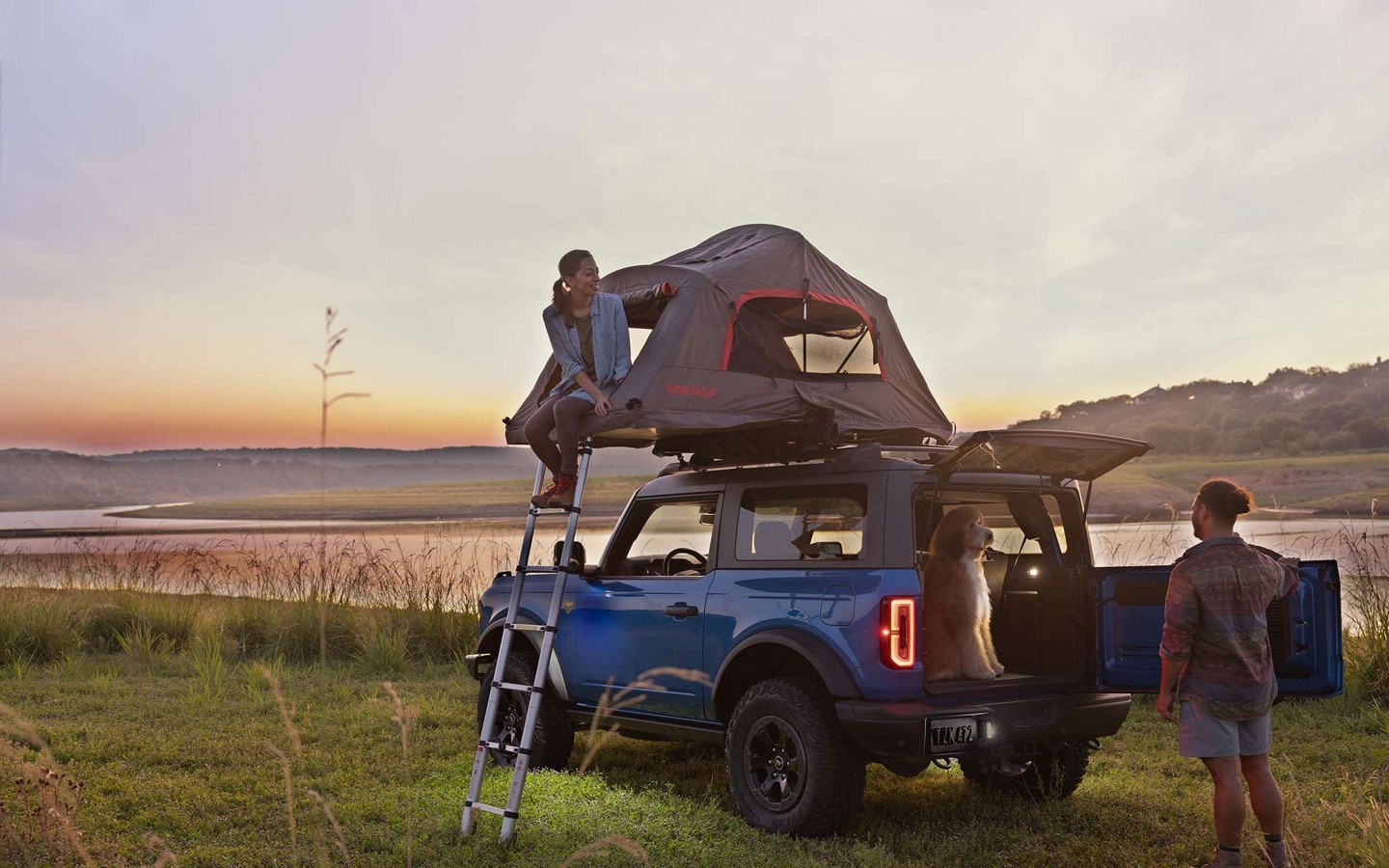 A couple setting up camp with a 2023 Ford Bronco® SUV with roof-mounted tent