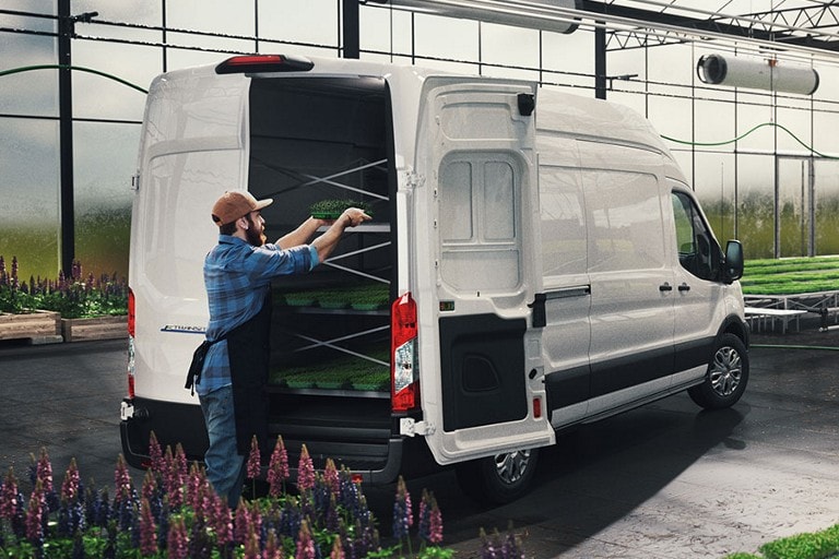 A 2022 Ford E-Transit™with a person loading products inside a greenhouse