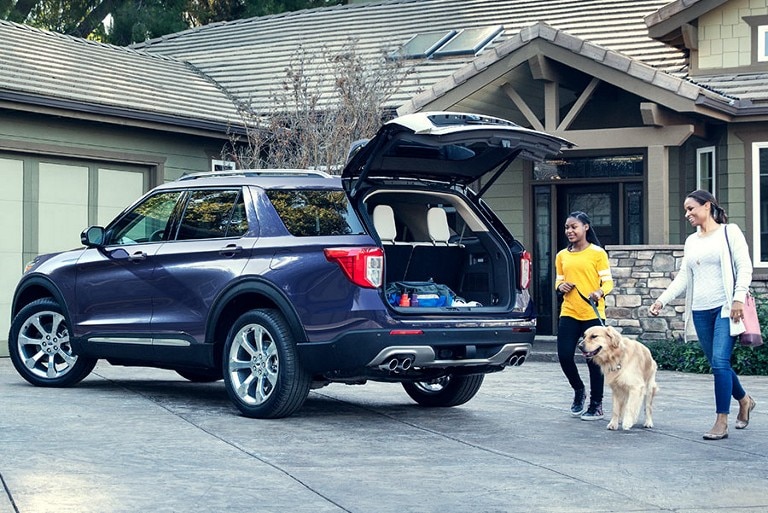 Two people with a dog approaching a 2020 Ford Explorer® SUV with liftgate open