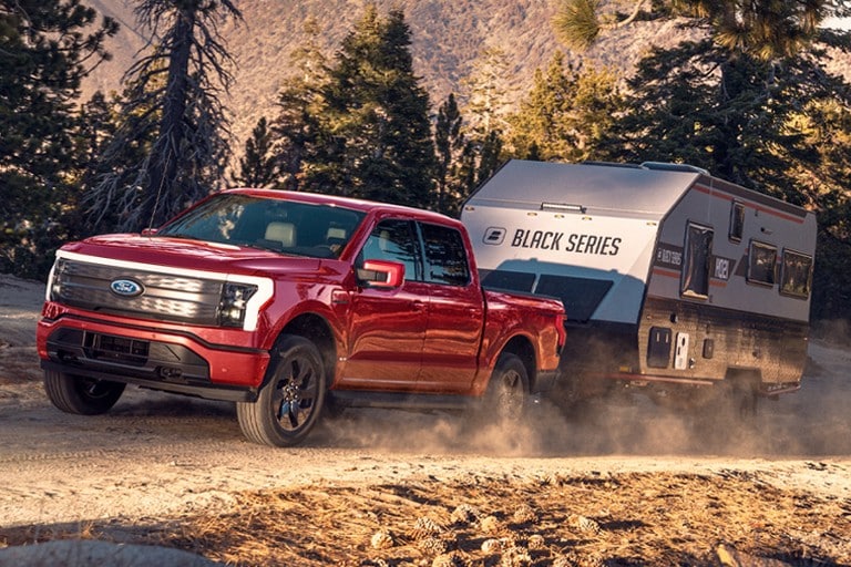 2022 Ford F-150® Lightning™ truck pulling a camper up a mountain