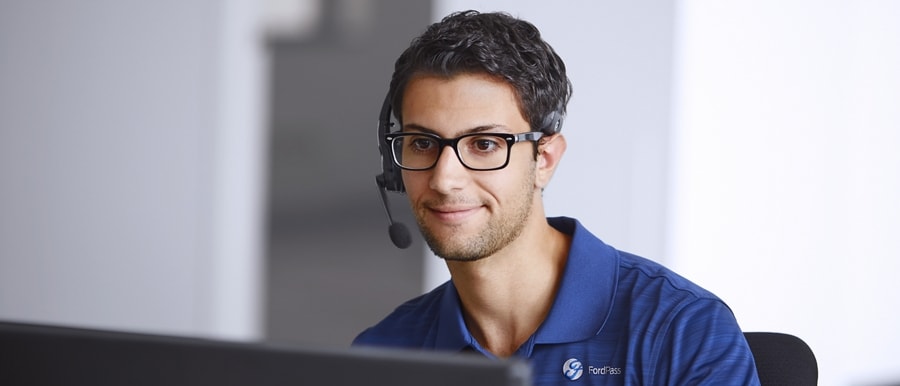 Man wearing microphone headset sits in front of computer screen