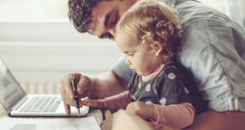 Worker working from home in front of laptop with baby in lap